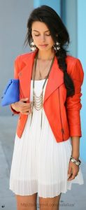 women's white pleated dress with orange leather bomber and statement necklace earrings